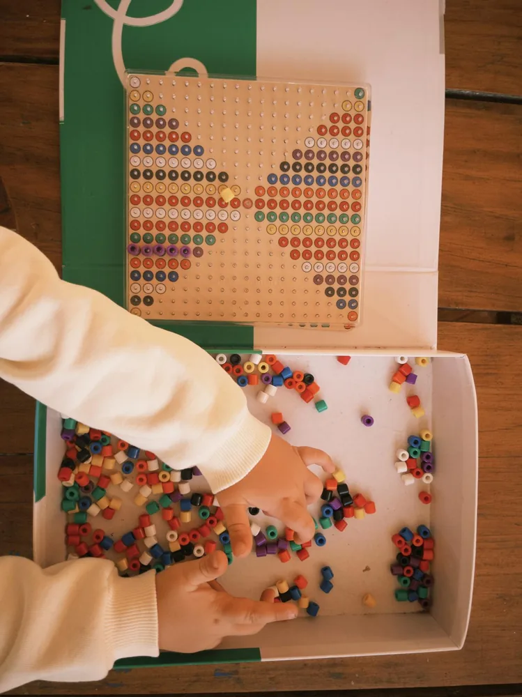 Hands choosing colourful beads for a butterfly pattern