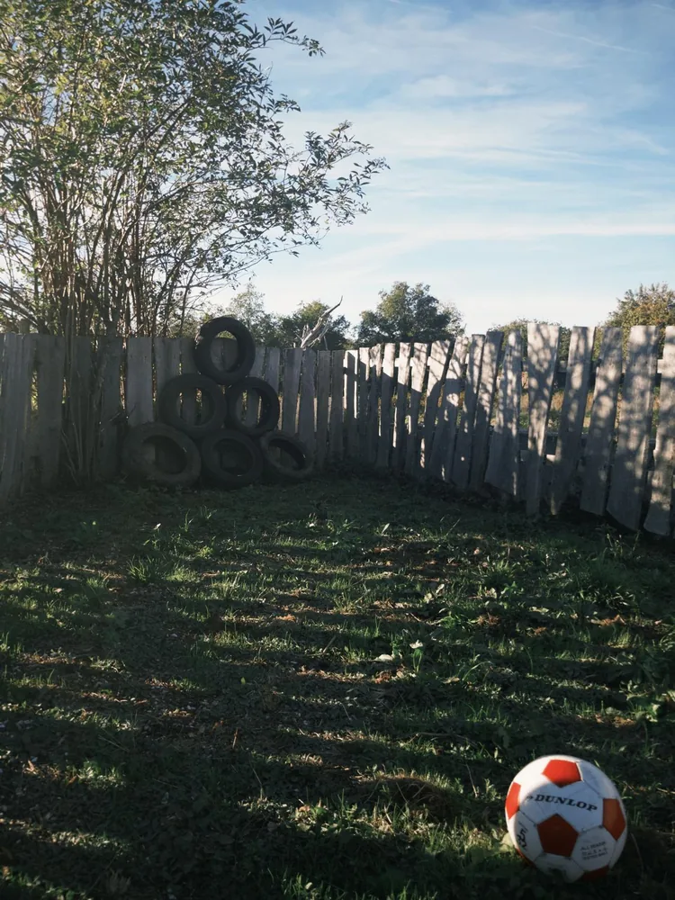 A ball and tyres beside a tree in the enclosed garden