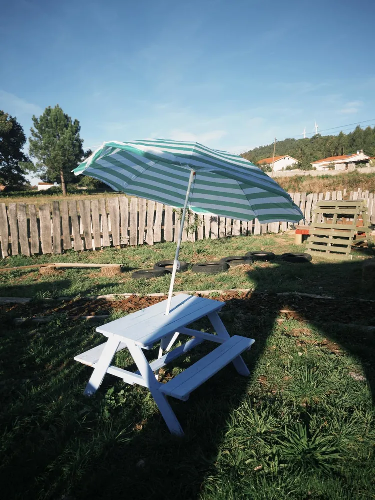 A picnic table under a striped parasol in the garden